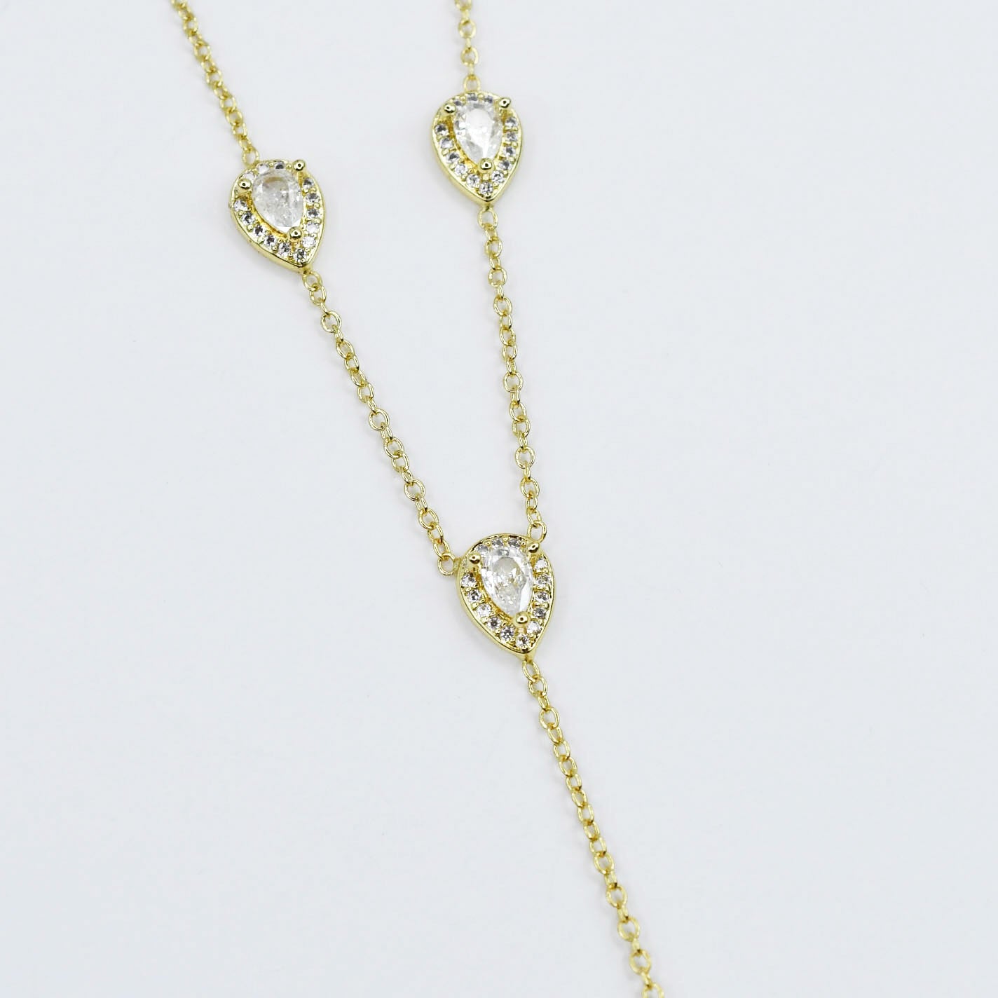 Dainty gold layered necklace, boutique wholesale jewelry, waterproof gold necklace, hypoallergenic and tarnish free statement accessory featuring a gold lariat necklace with clear teardrop pendants